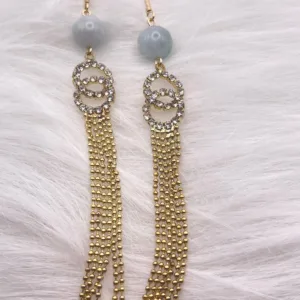 Chic earrings with gray round beads and flowing gold tassels for a refined yet playful look." This jewelry piece is designed to add a touch of sophisticated movement and modernity to any outfit, making it a versatile addition to any collection.