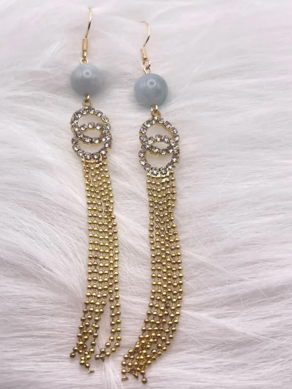 Chic earrings with gray round beads and flowing gold tassels for a refined yet playful look." This jewelry piece is designed to add a touch of sophisticated movement and modernity to any outfit, making it a versatile addition to any collection.