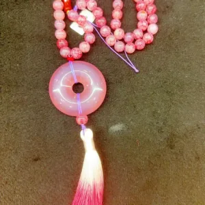 Pink beaded necklace with circular pendant and tassel
