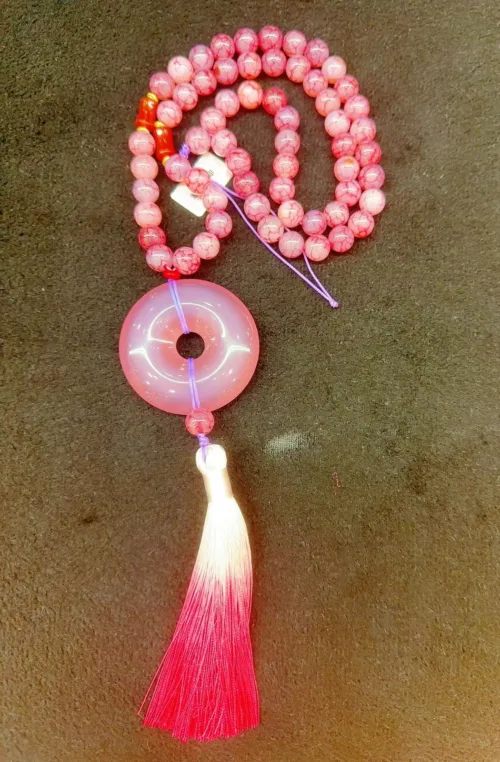 Pink beaded necklace with circular pendant and tassel