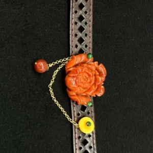 Carved flower pendant on perforated leather strap.
