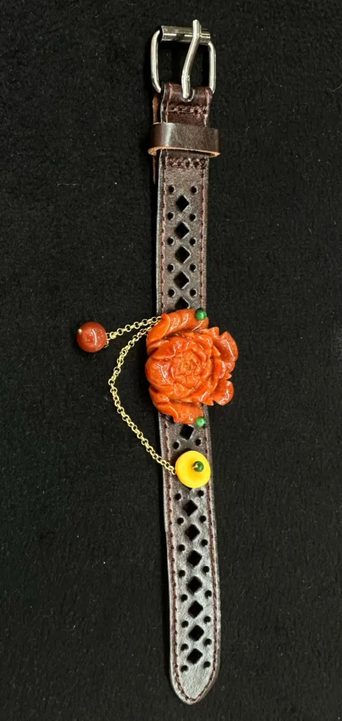 Carved flower pendant on perforated leather strap.