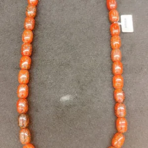 Orange beaded necklace on gray background.