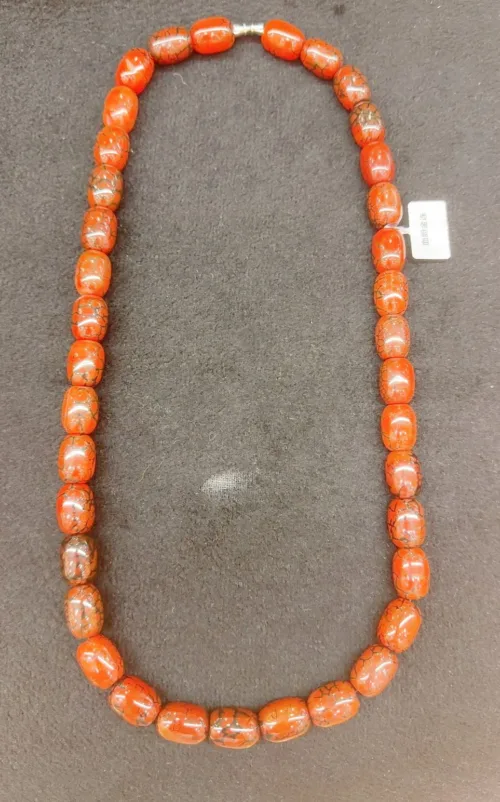 Orange beaded necklace on gray background.