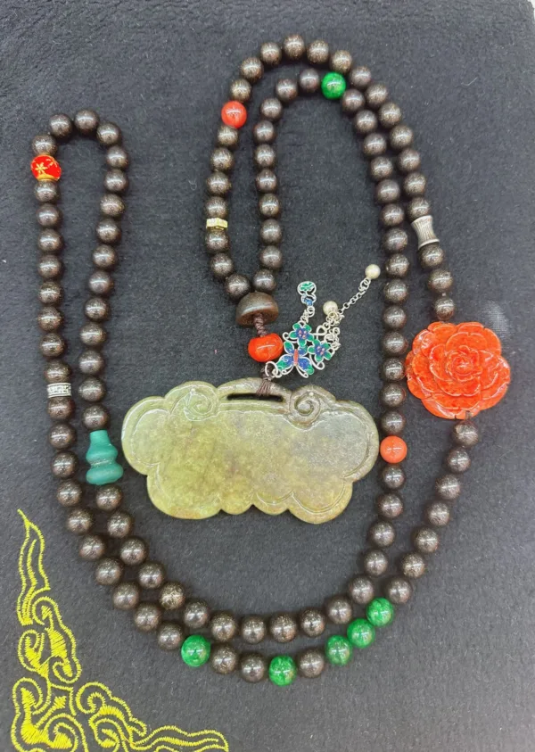 Traditional beaded necklace with jade pendant and flower.