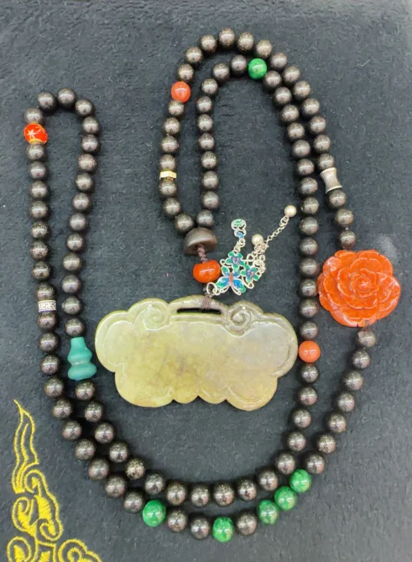 Beaded necklace with jade pendant and floral brooch.