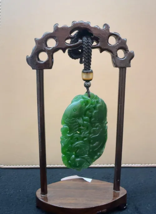 Carved jade pendant on display stand.