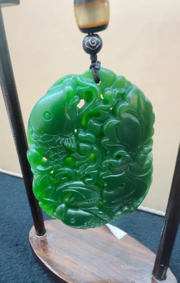 Intricate green jade pi xiu carving on stand.