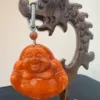 Carved wooden stand with hanging laughing Buddha ornament.