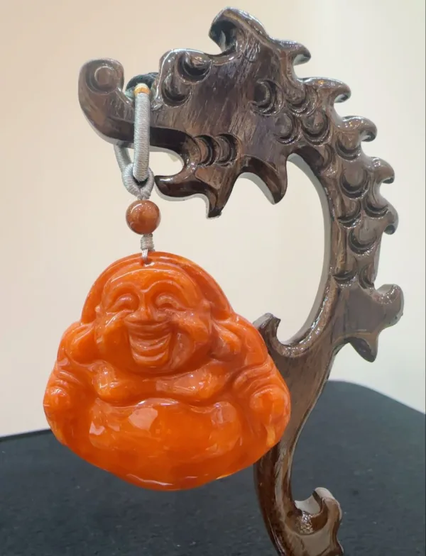 Carved wooden stand with hanging laughing Buddha ornament.