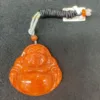 Orange jade Buddha pendant with price tag.