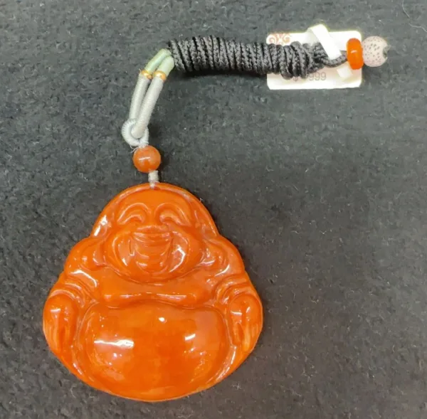 Orange jade Buddha pendant with price tag.