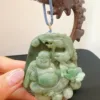 Carved jade Buddha pendant on wooden stand.