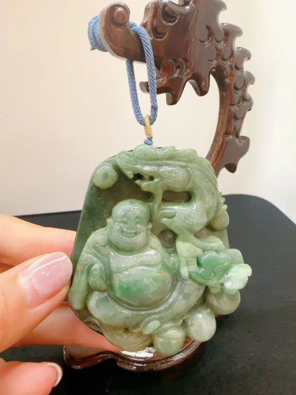 Carved jade Buddha pendant on wooden stand.