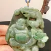 Carved jade pendant with Buddha design held in hand.