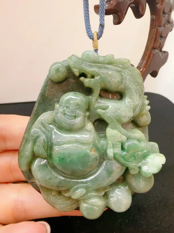 Carved jade pendant with Buddha design held in hand.