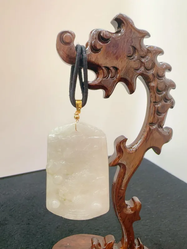 Carved wooden stand displaying jade pendant.