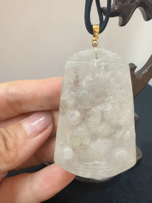 Hand holding carved jade pendant.