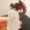 Carved jade pendant with wooden stand.