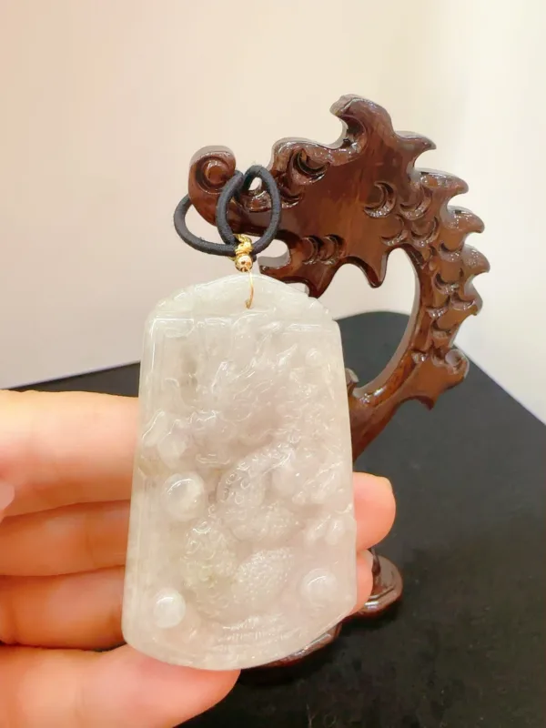 Carved jade pendant with wooden stand.