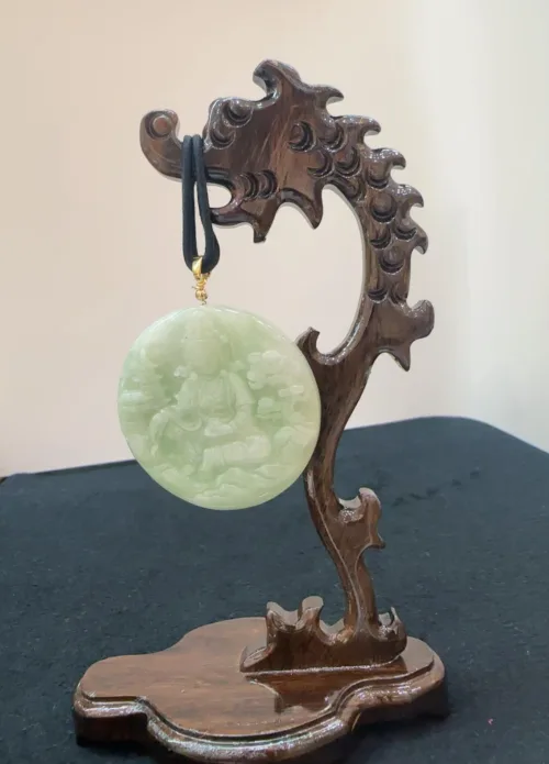 Carved jade pendant on wooden stand