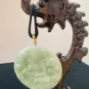 Carved jade pendant on wooden stand.