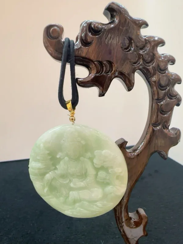 Carved jade pendant on wooden stand.