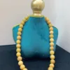 Golden beaded necklace on blue stand.