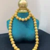 Yellow bead necklace on blue display stand.