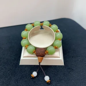 Green bead bracelet with wooden accents on display stand.