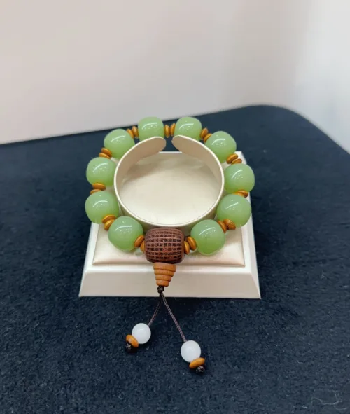 Green bead bracelet with wooden accents on display stand.