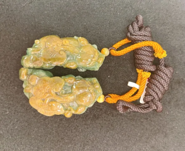 Carved jade dragon pendant with knotted cords.