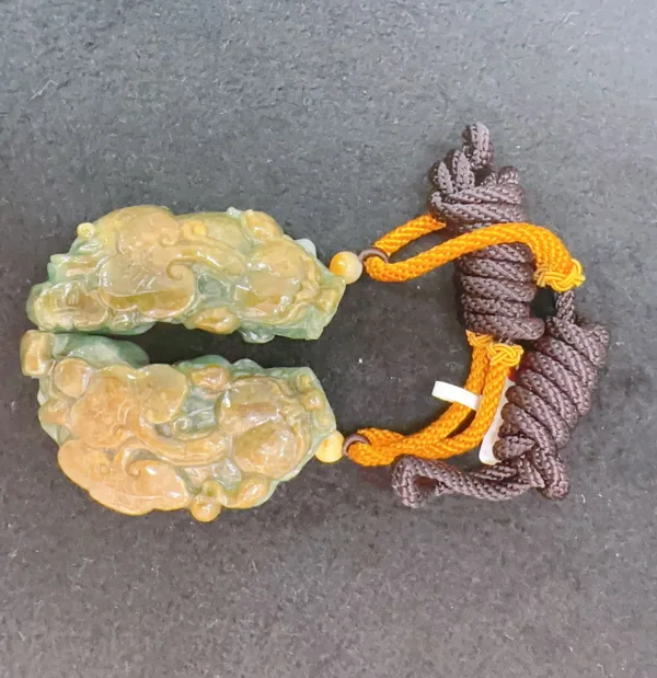 Jade pendant with orange tassel on dark background.