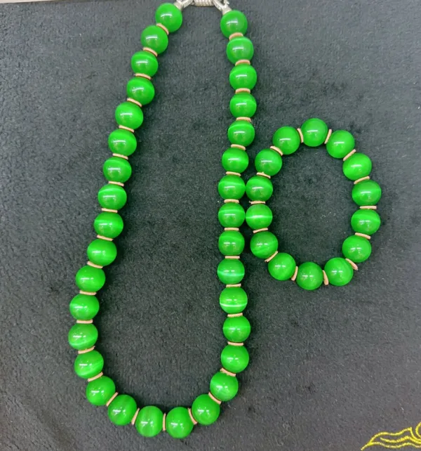 Green bead necklace and bracelet on black background