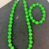 Green beaded necklace and bracelet set on black.