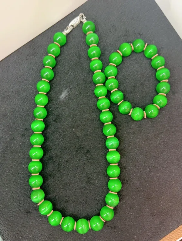 Green beaded necklace and bracelet set on black.