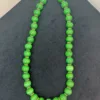 Green bead necklace on black background.
