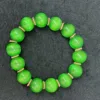 Green bead bracelet on black surface.