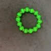 Green beaded bracelet on dark background.