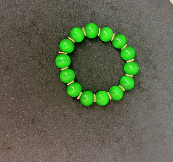 Green beaded bracelet on dark background.