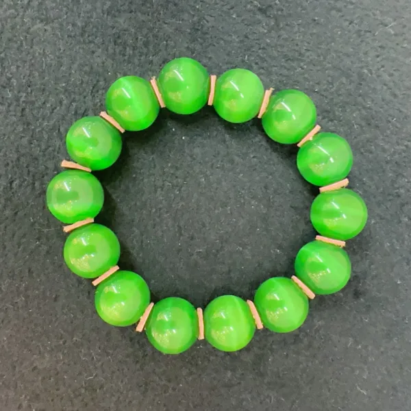 Green beaded bracelet on dark background.