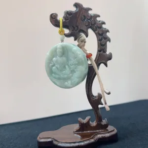 Carved jade pendant on wooden stand