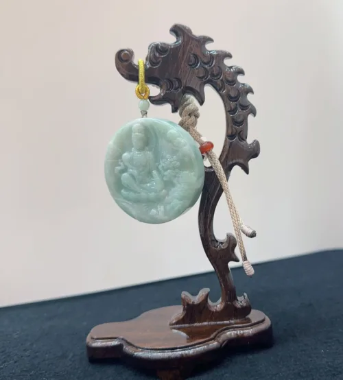 Carved jade pendant on wooden stand