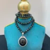 Elegant necklace with pendant on blue display stand.