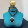 Elegant necklace on turquoise display stand.