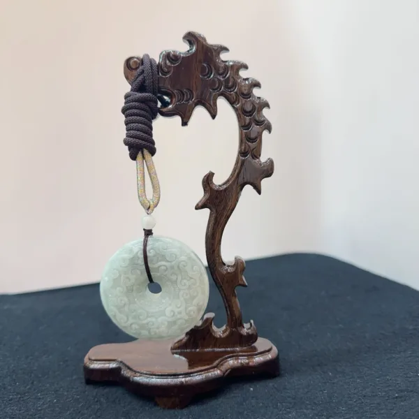 Carved wooden stand with jade disc pendant.