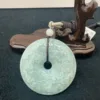 Carved jade disc on wooden stand with price tag.