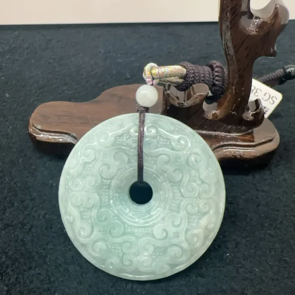 Carved jade disc on wooden stand with price tag.