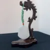 Carved wooden stand with jade pendant.