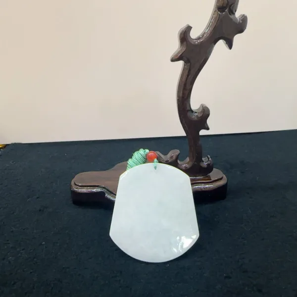 White jade pendant on wooden display stand